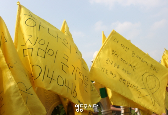 16일 오후 서울 여의도 국회 앞에 도착한 단원고 2학년 학생들이 꽂아둔 노란 깃발이 국회 담벼락에 걸려 있다.