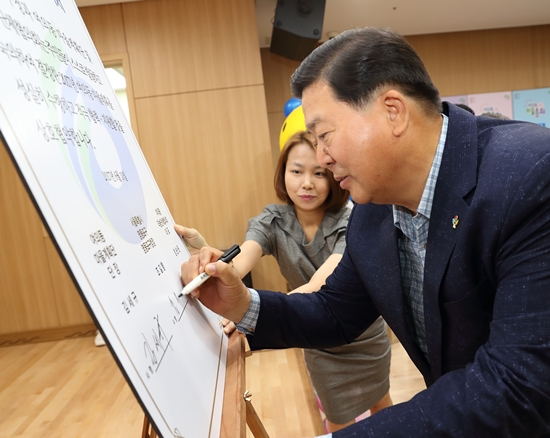 조길형 영등포구청장이 10일 여의도복지관 및 자매공원에서 열린 여의동 마을총회에 참석해 민·관 협약서에 서명을 하고 있다.