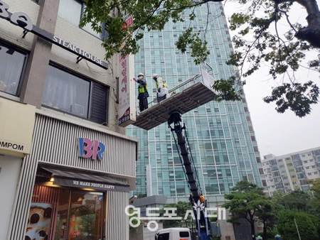▲서울시 옥외광고협회 영등포지부 재해방재단이 크레인을 이용해 옥외광고물에 대한 안전 점검을 시행하고 있다. Ⓒ영등포시대