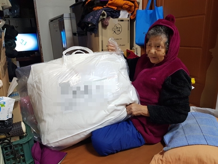 ▲저소득 홀몸 어르신이 이불을 받는 모습