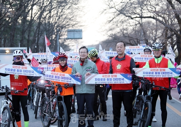 ▲영등포구 자전거 연맹회원들이 본지의 요청에 최호권 영등포구청장과 함께 ‘국민과 함께, 자유로운 통일 대한민국’이 적힌 작은 현수막을 들고 퍼포먼스를 펼치고 있다. ⓒ영등포시대 