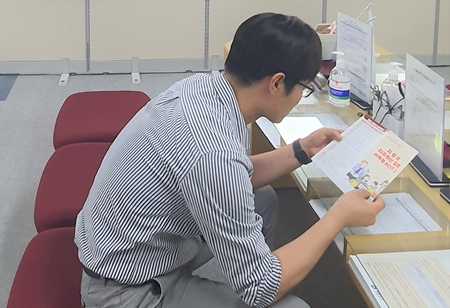 ▲‘지방세 자주하는 질문 세목별 BEST3“ 리플렛을 구청 민원대에서 보고 있는 민원인